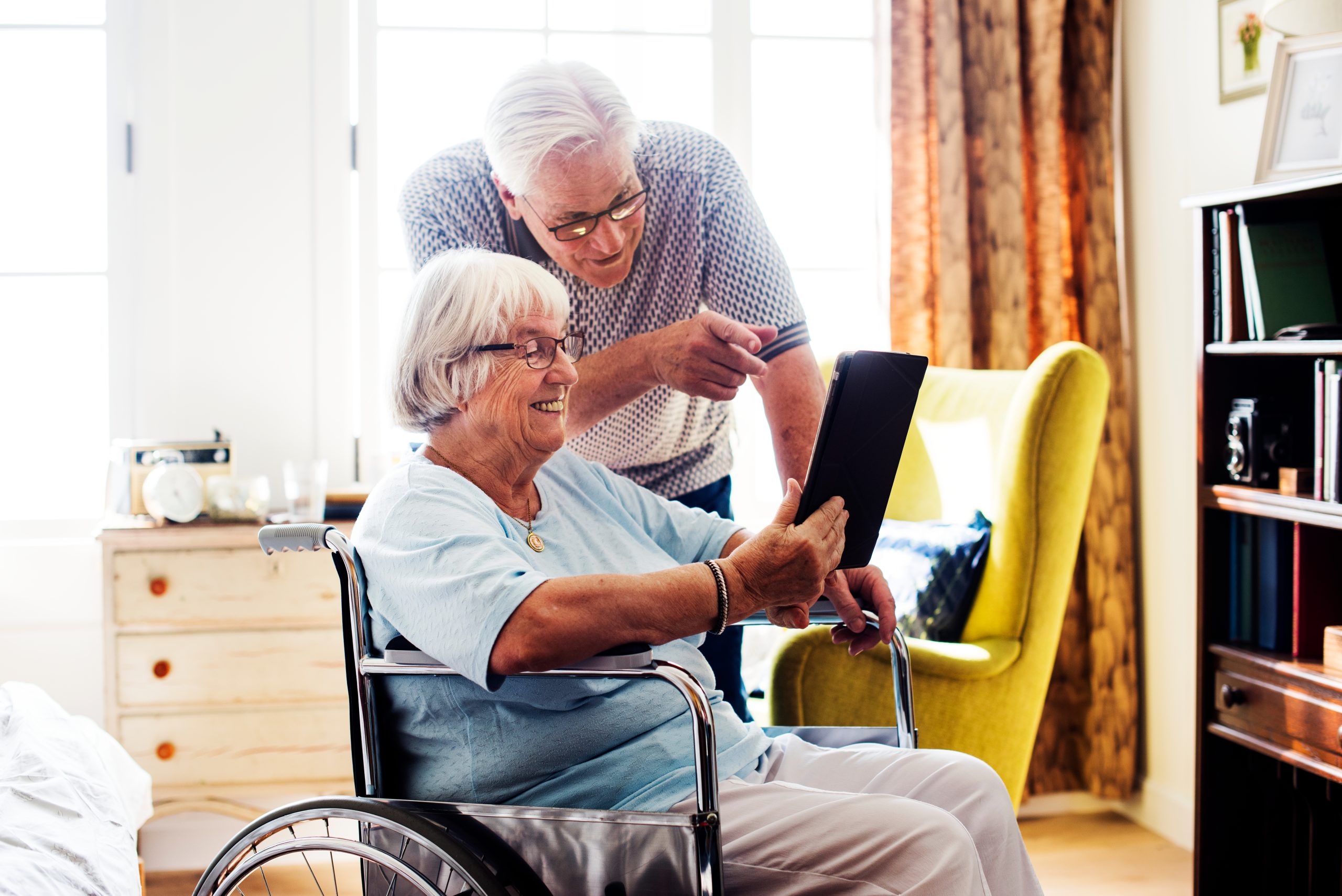 Elderly couple looking at an iPad and smiling