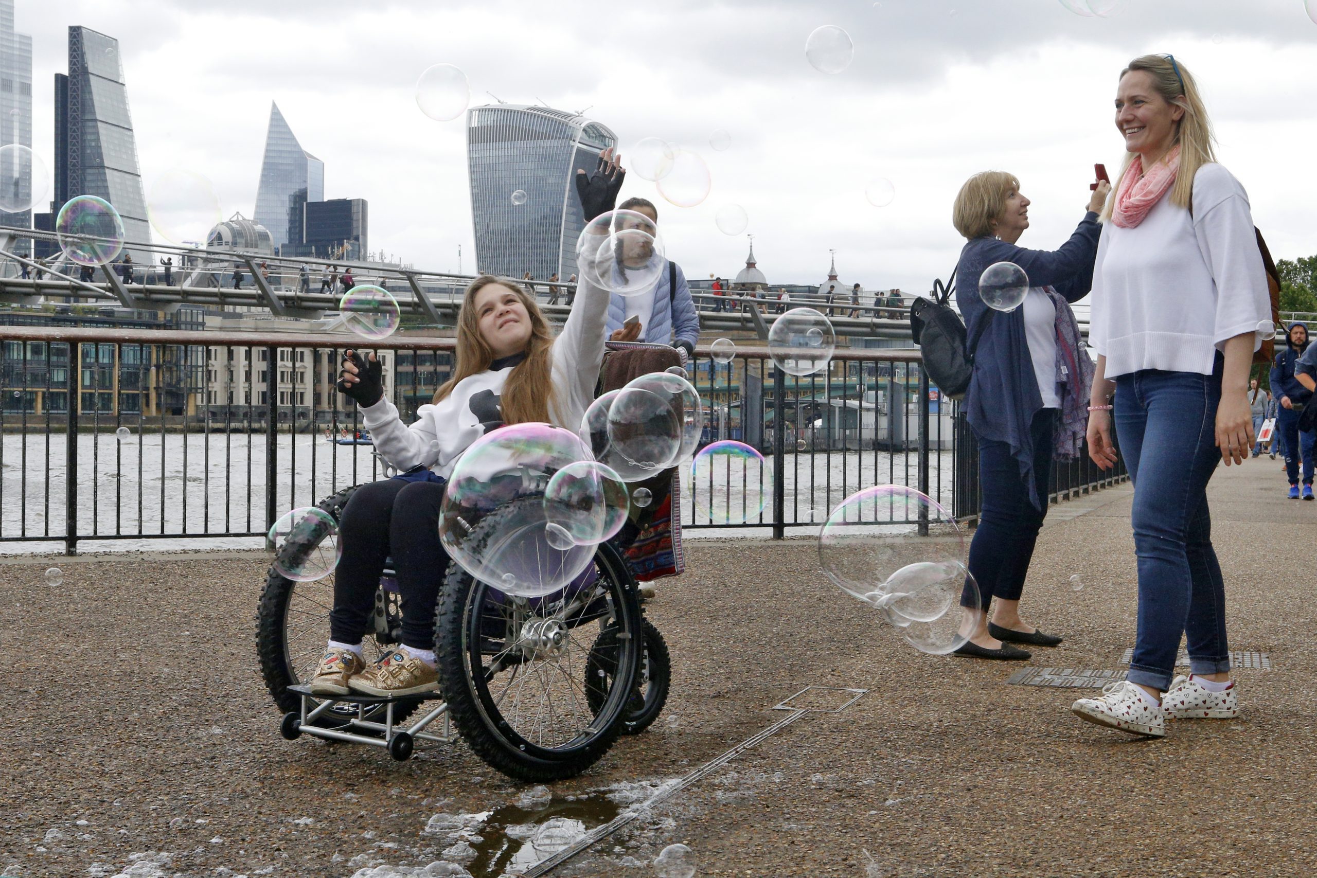 A woman in a wheelchair is enjoying a day out in Embankment, London, with friends