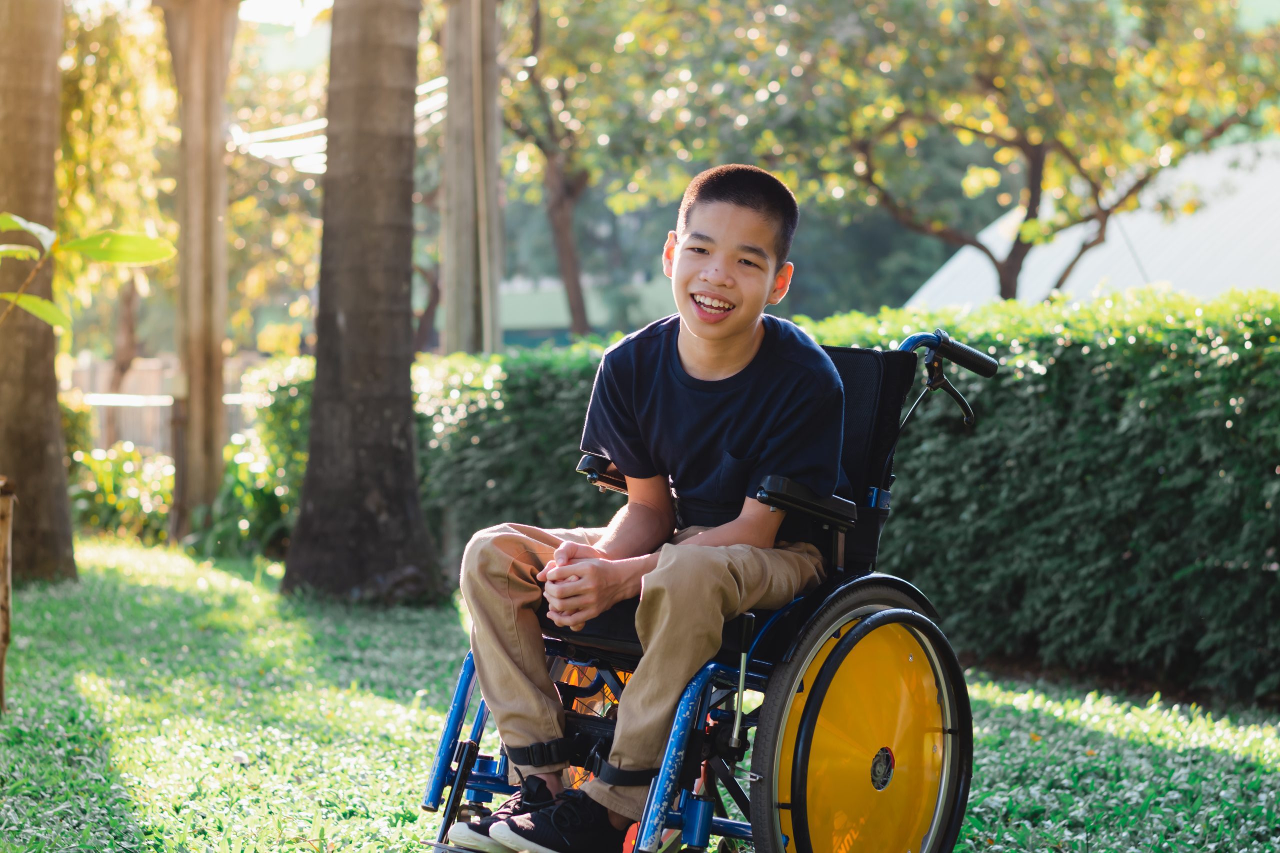 A boy in a wheelchair smiling in the garden