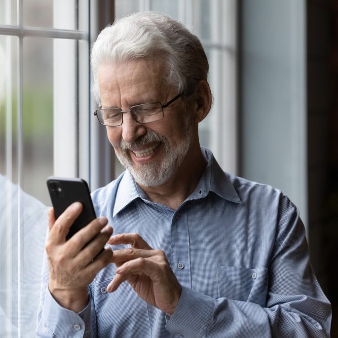 Older man smiling at phone screen