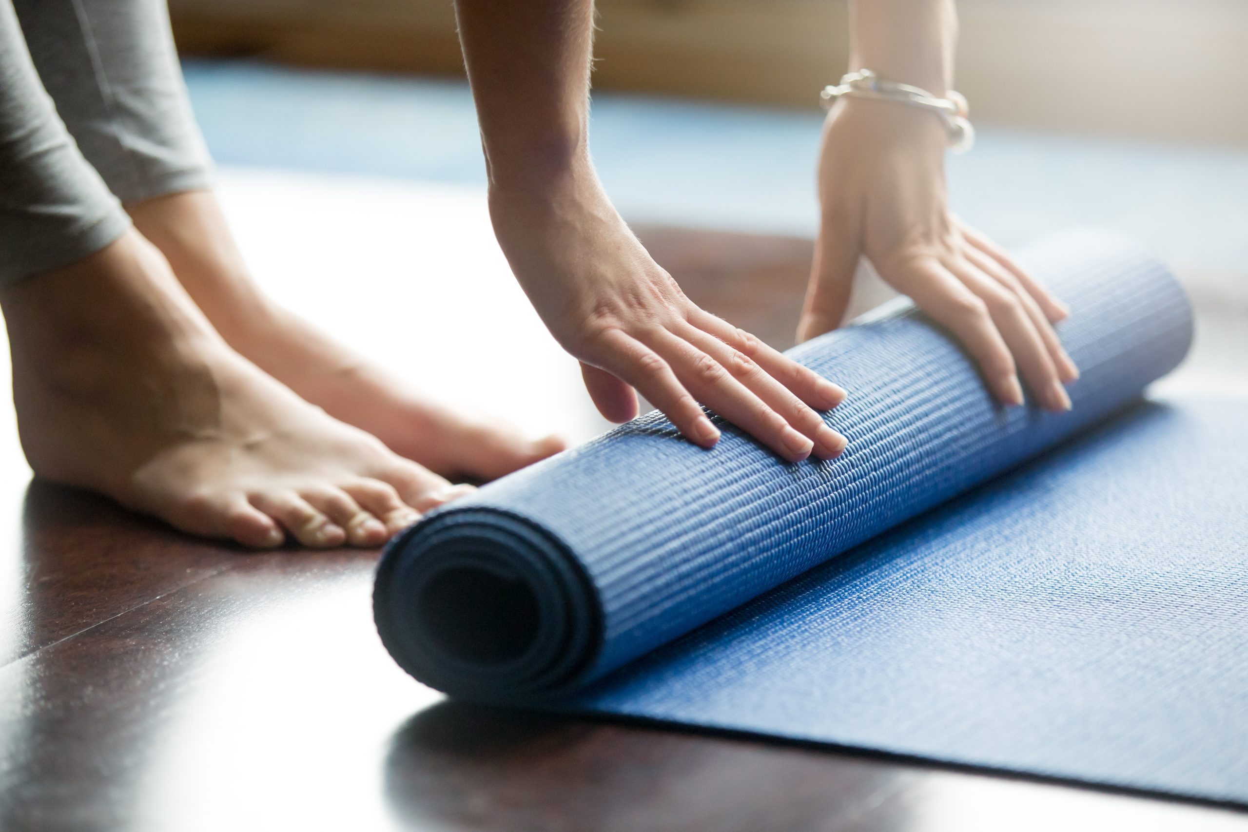 Close up of a woman rolling up a yoga mat