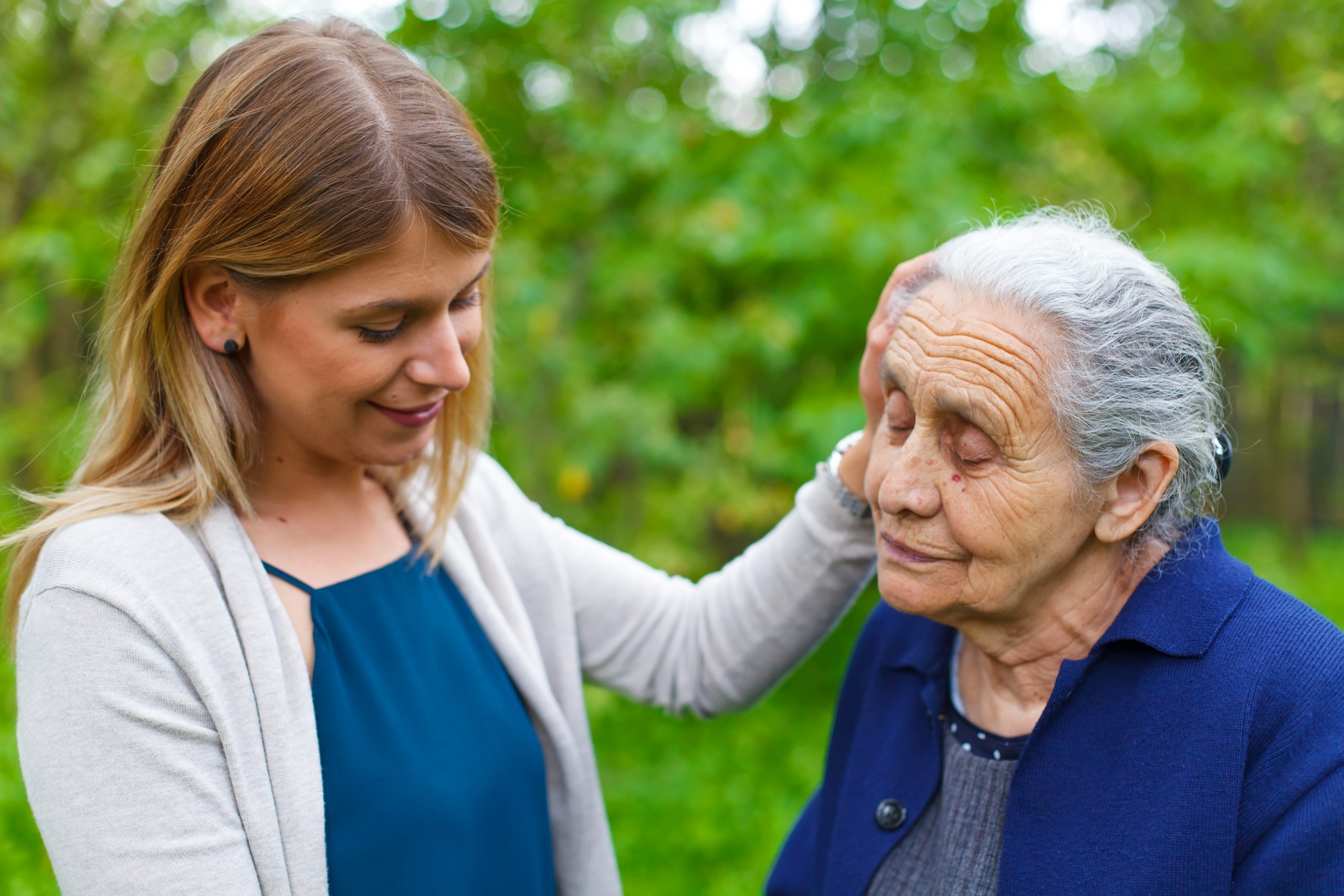Elderly woman standing with a supportive younger woman