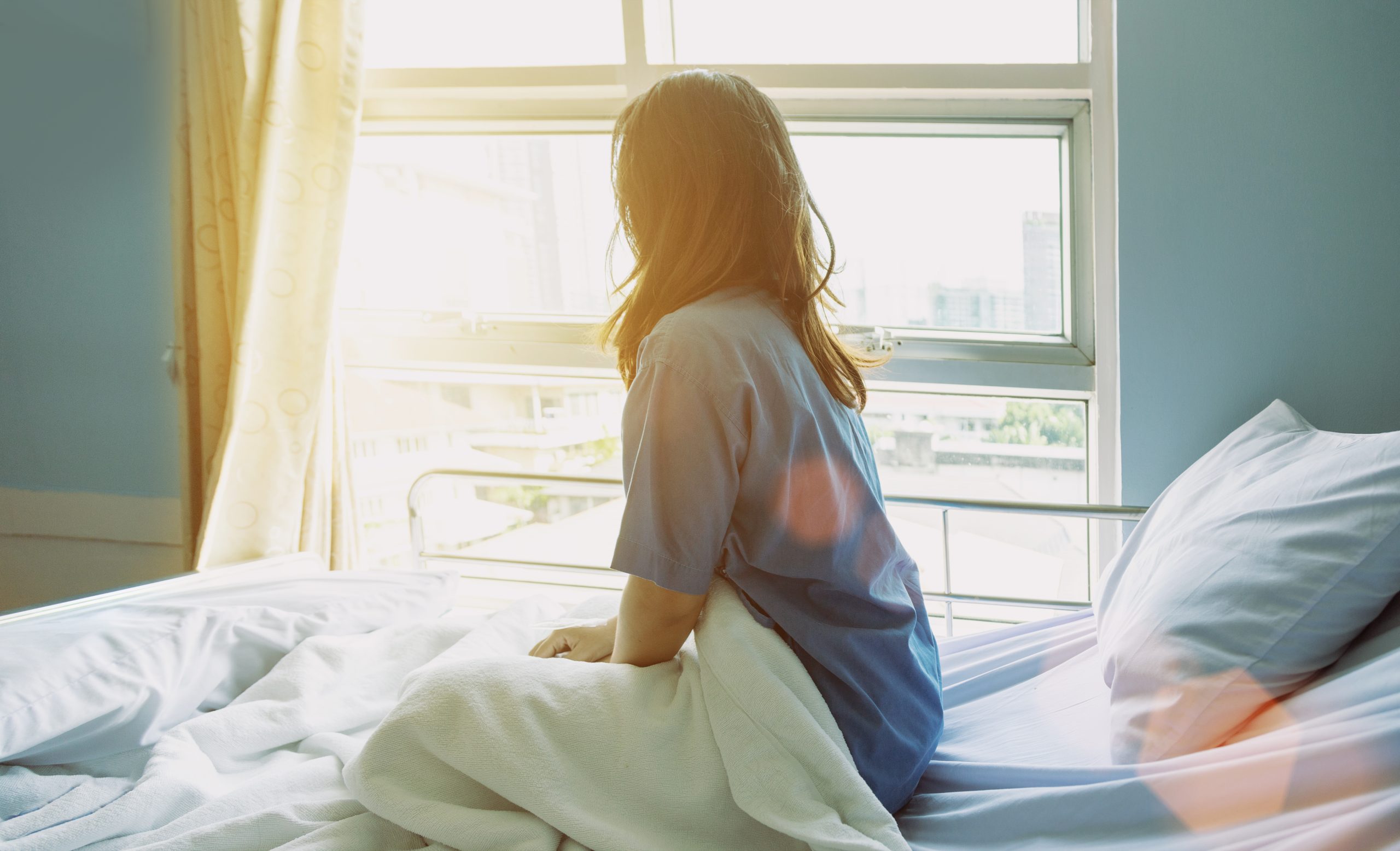 Woman in bed looking out the window after surgery