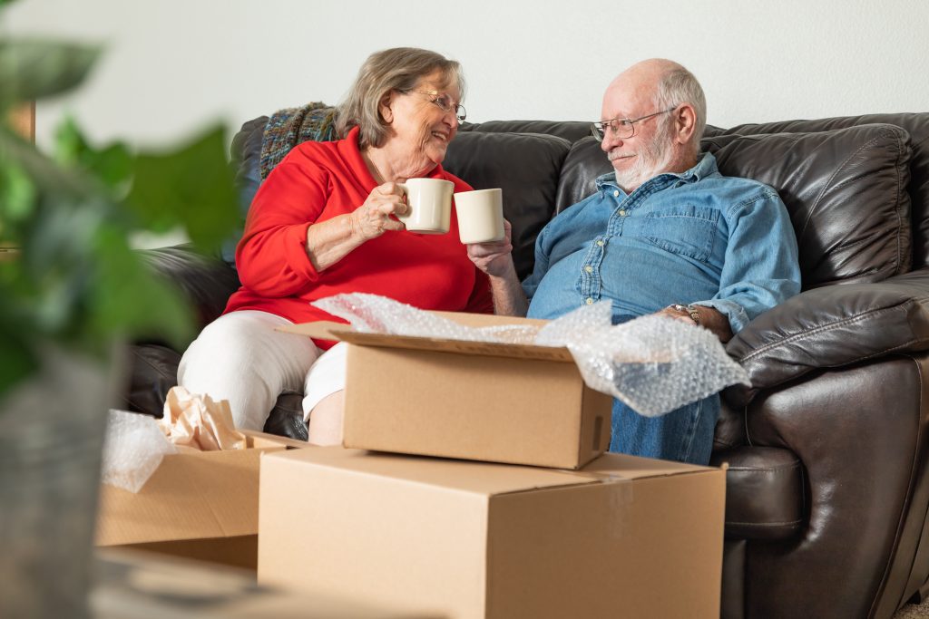 Senior couple enjoying a hot drink on the sofa, after moving house