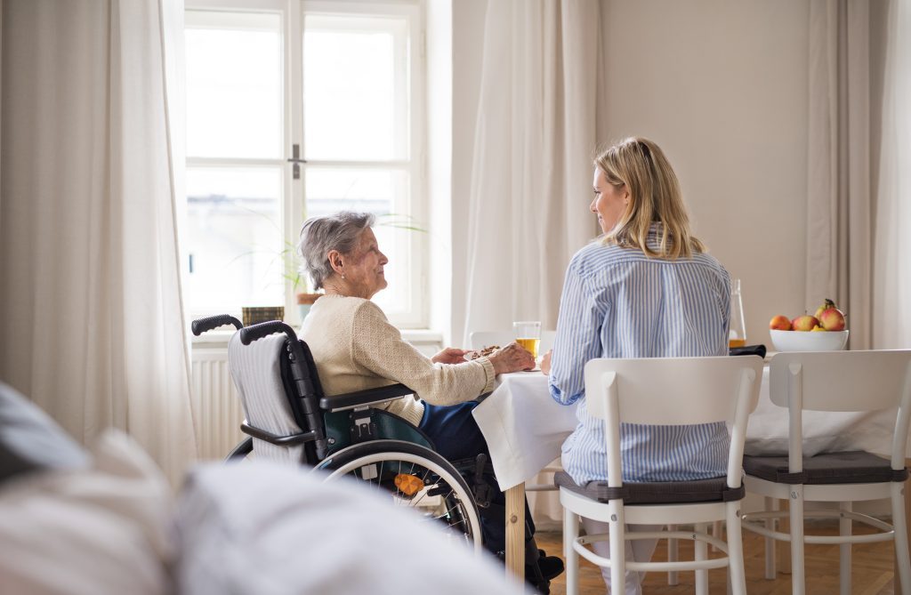 An older lady in a wheelchair sitting at a table with a younger woman