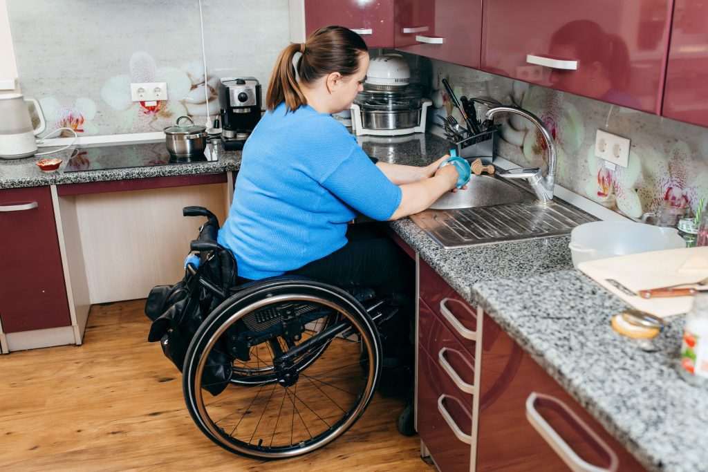 Lady in a wheelchair washing dishes at her accessible sink