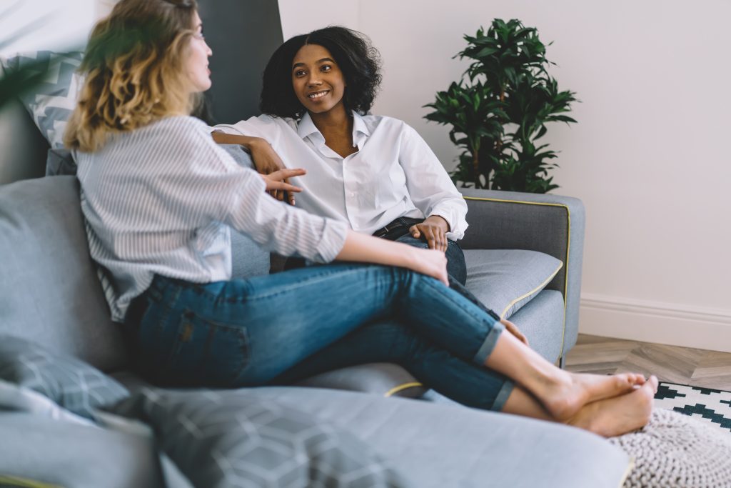 Two female friends sitting on a sofa and talking