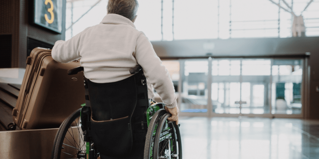 Person in a wheelchair grabbing their suitcase in an airport