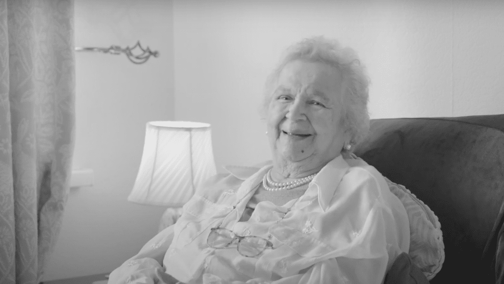 A photo of Isabella, an older lady sitting on her sofa and smiling